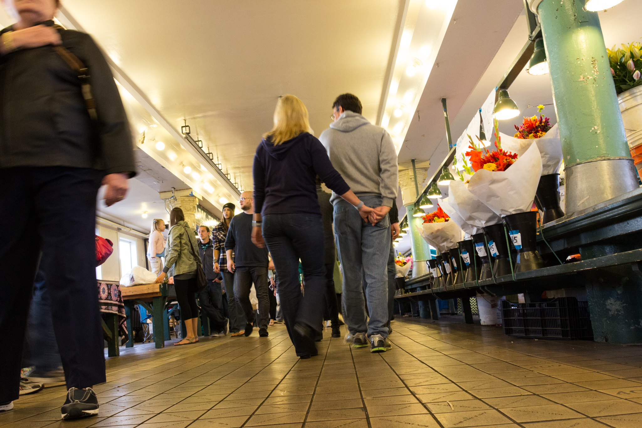 A couple walks hand-in-hand down aisles of street market.