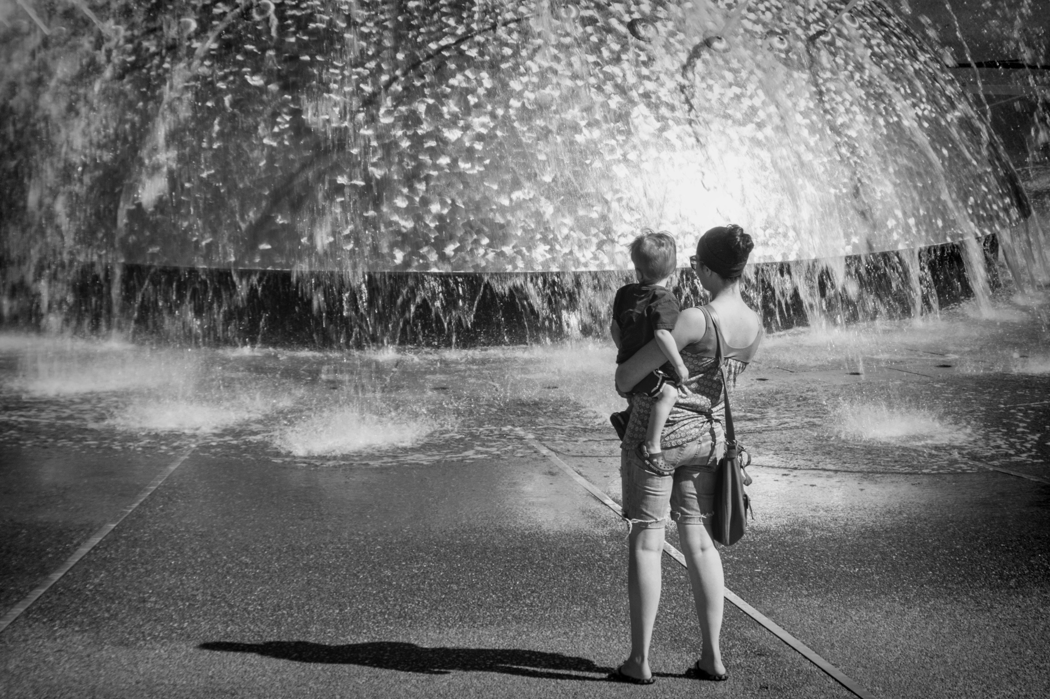 black & white of mother and son looking at the water fountain