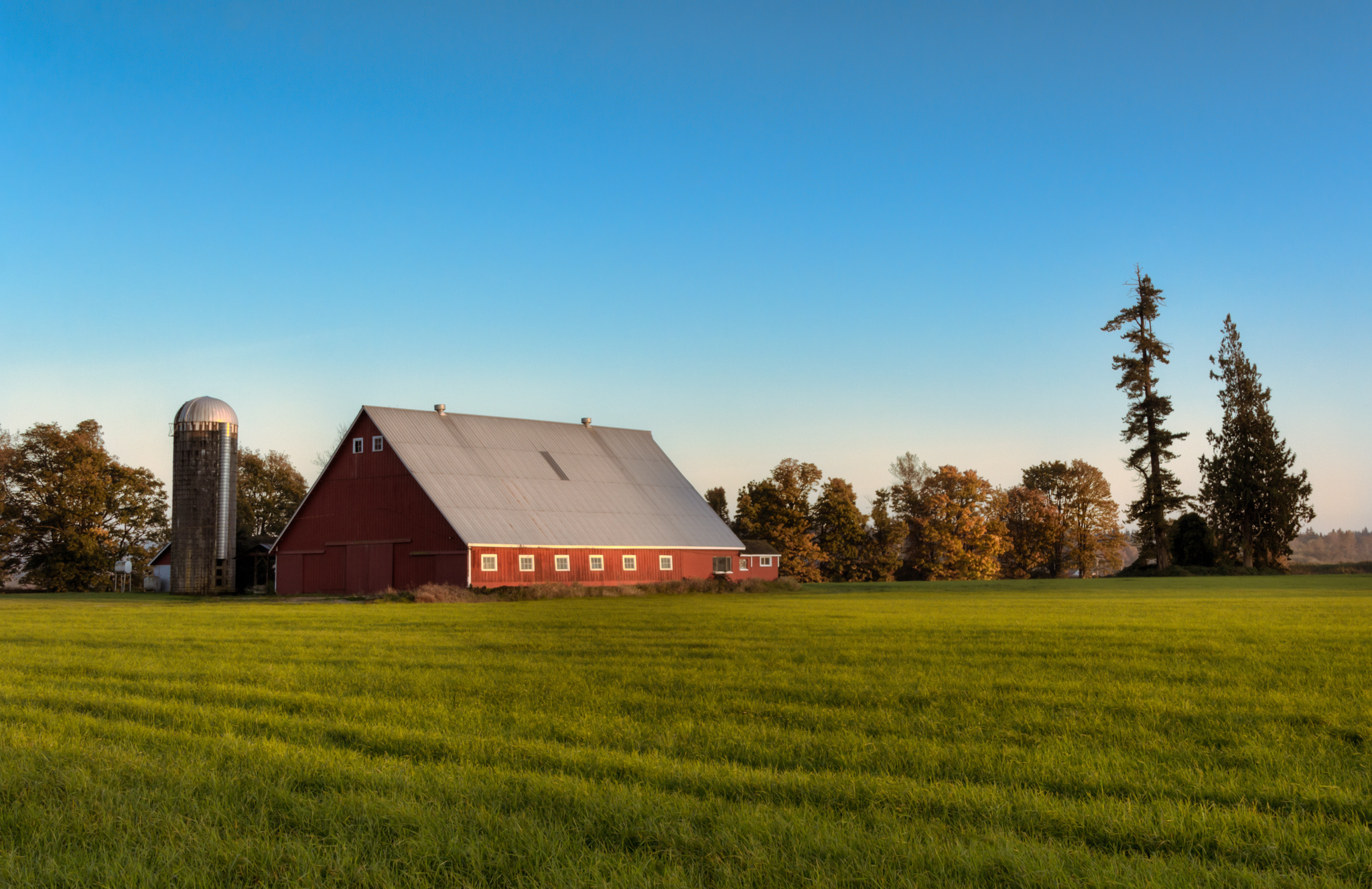 A red barn with green field below and blue sky above.