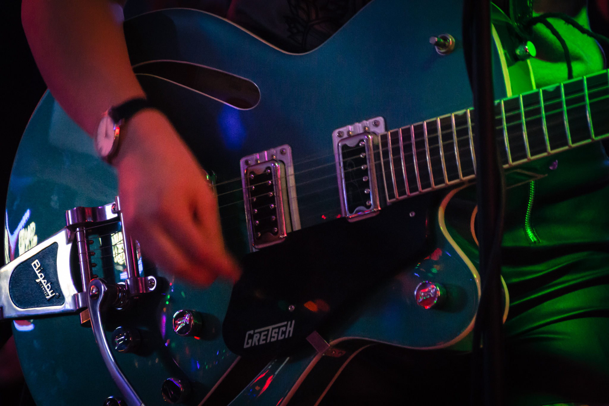 Hand strumming blue electric guitar.