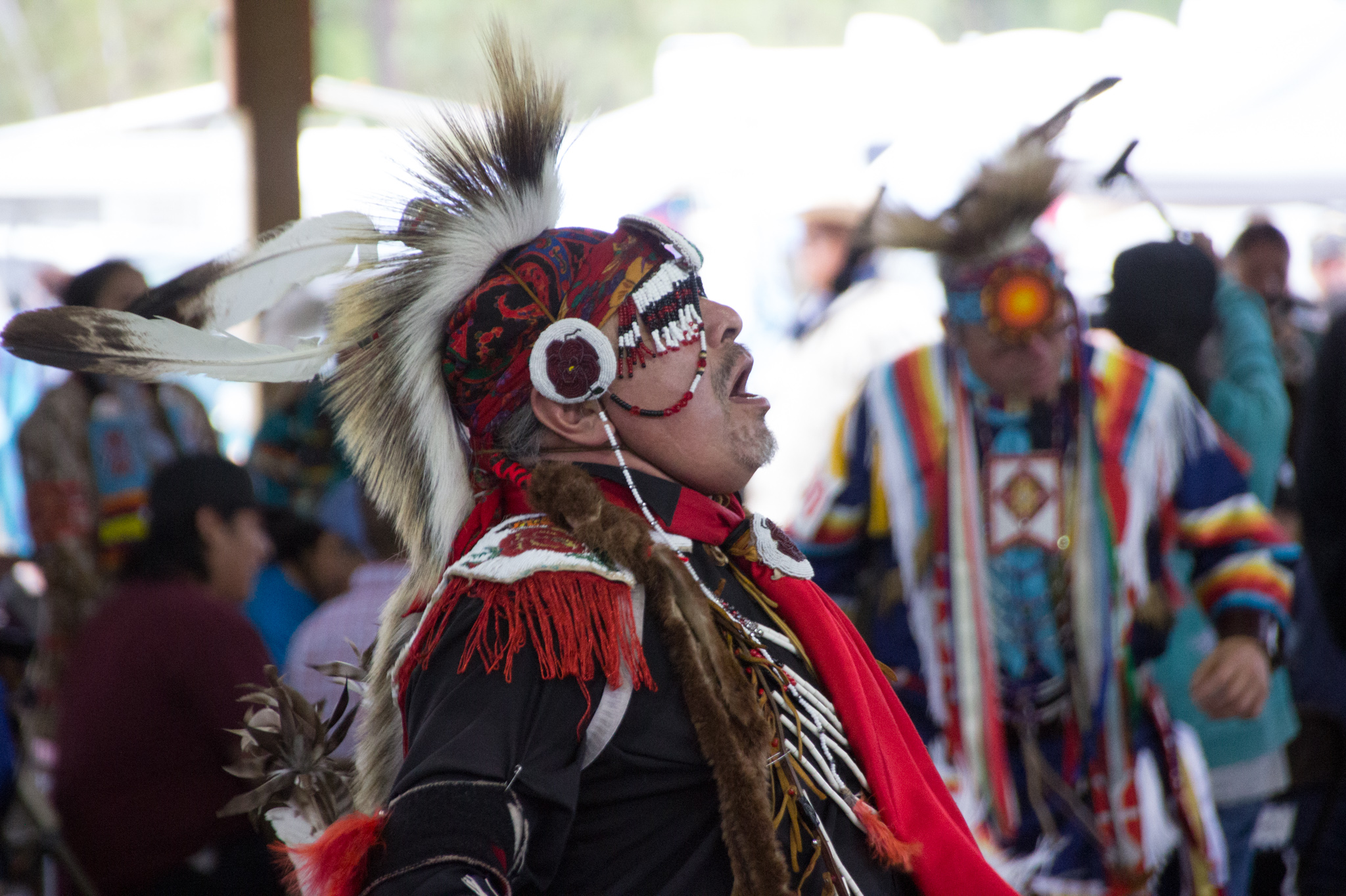 A male dancer sings while dancing at a pow wow.
