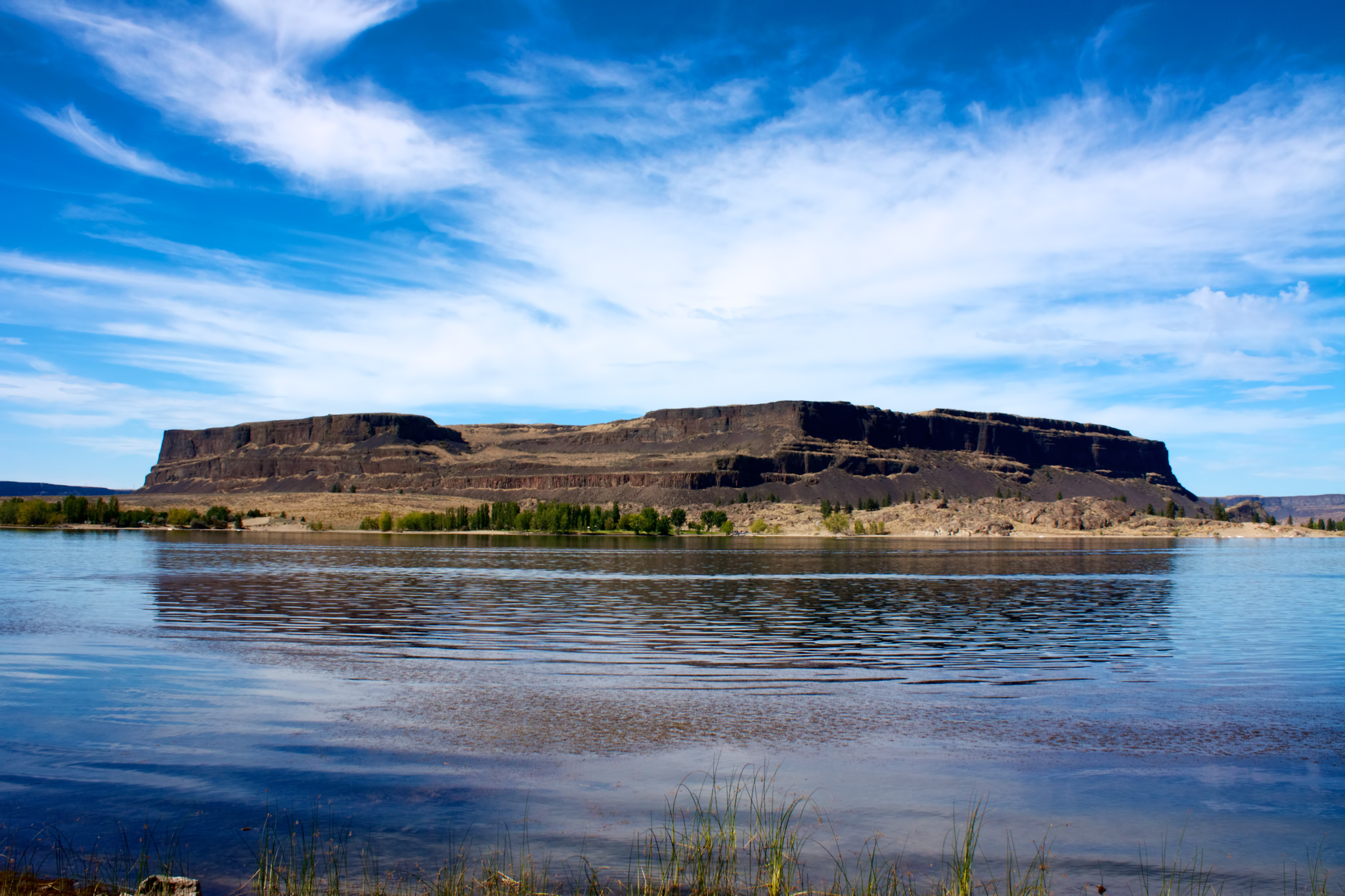 Steamboat rock, an island formation in Banks lake, with blue sky above and reflecting waters below